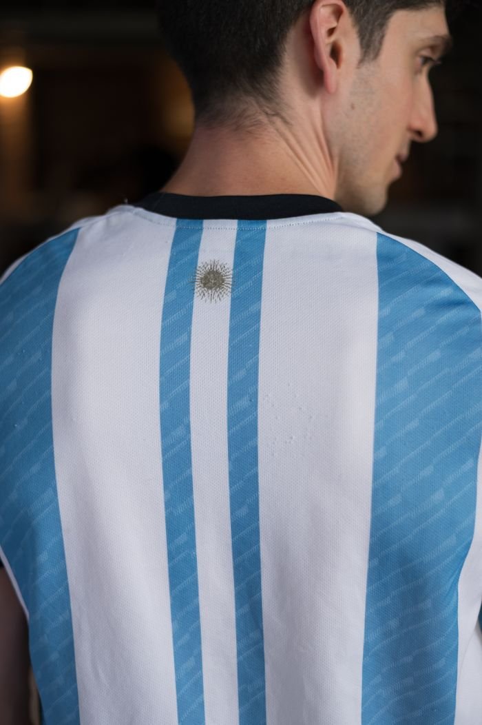 Man wearing Argentina's striped football jersey indoors, showcasing national pride.